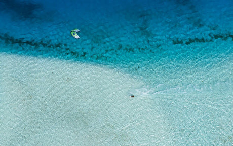 Duotone Neo SLS 2027 Kiteboard, weiß-blau, Luftaufnahme über türkisem Wasser