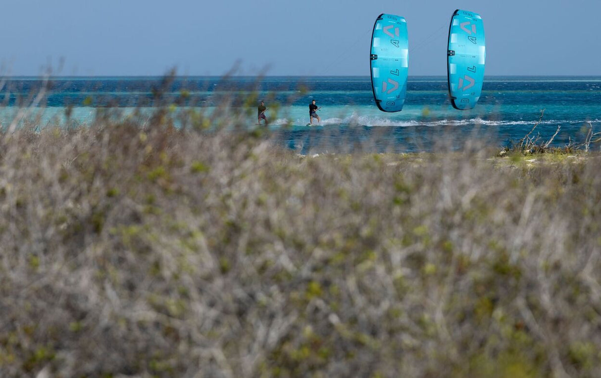 Duotone Evo D/LAB 2027 Kite in Blau, Sportler am Strand mit Meer im Hintergrund