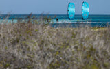 Duotone Evo D/LAB 2027 Kite in Blau, Sportler am Strand mit Meer im Hintergrund