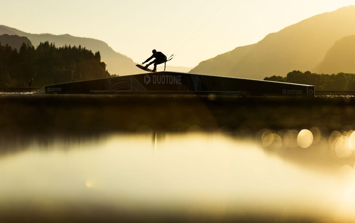 Duotone TS Park 2027 Wakeboard in schwarzer Farbe auf Wasser, Sportler in Action beim Trick auf dem Board
