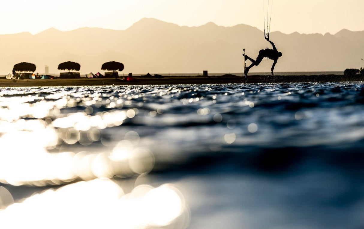 Duotone Shred 2027 Kiteboard in Aktion über Wellen, Kitesurfer in Silhouette bei Sonnenuntergang