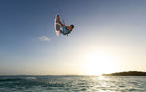 Duotone Blur SLS 2027 Kiteboard mit Sportler in Sprung über Wasser, Frontalansicht gegen Himmel