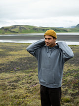 ION Ionic Fisherman 2026 Hoodie blaugrau, Mann trägt gelbe Mütze in Landschaft, Frontalansicht