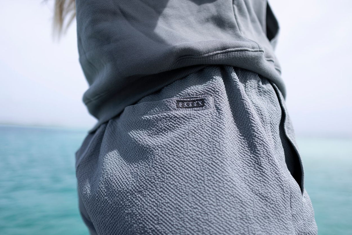 ION Tally 2.5 Boardshorts Damen in Grau, getragen am Meer, Detailansicht der Hüfte und Oberschenkel