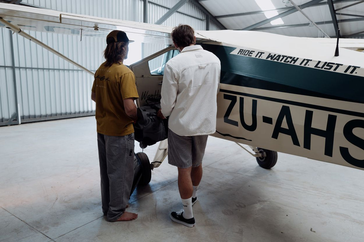 ION Mood 2026 Kiteboard wird von zwei Personen in einer Werkstatt neben einem Flugzeug inspiziert