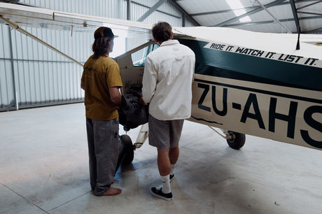 ION Mood 2026 Kiteboard wird von zwei Personen in einer Werkstatt neben einem Flugzeug inspiziert