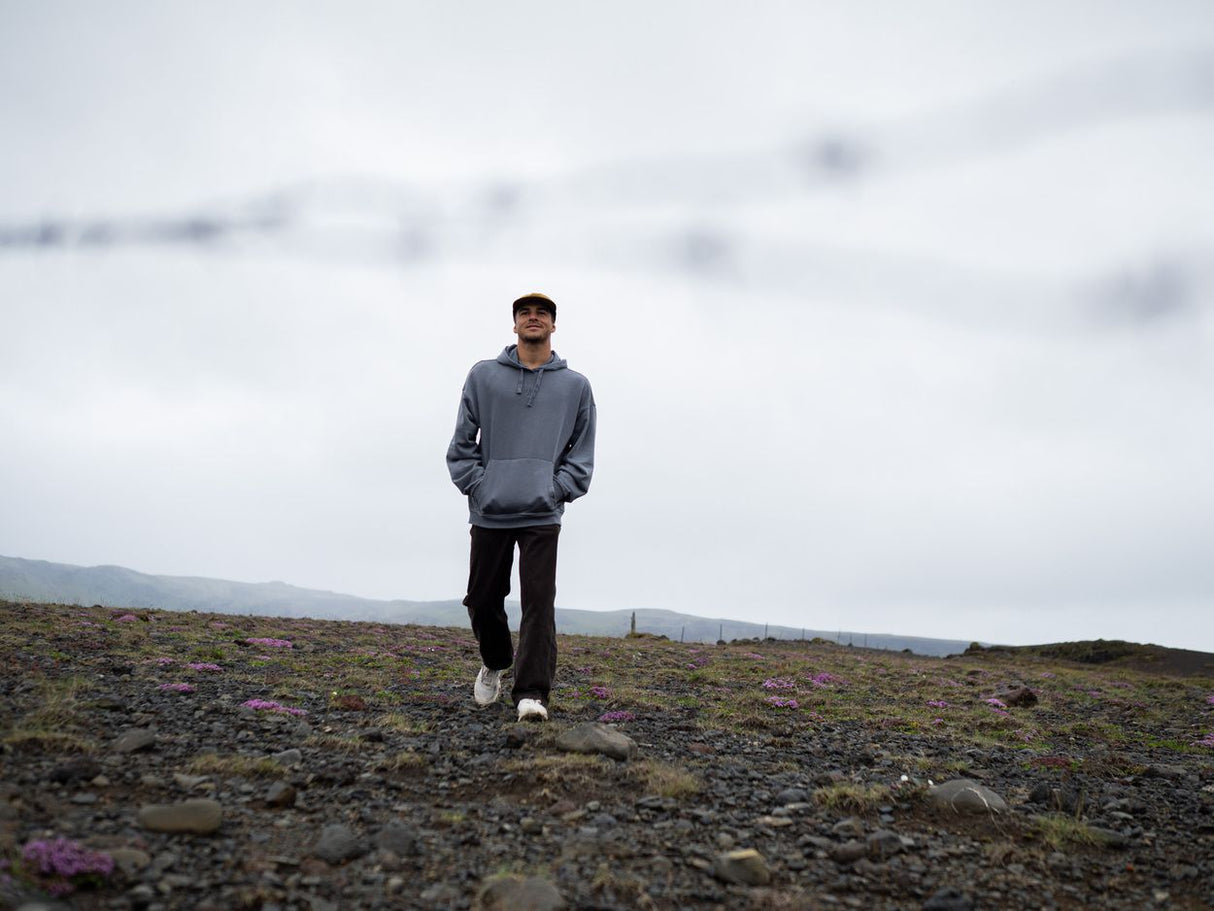 ION Surfing Elements Hoody 2026 in Blaugrau, Frontalansicht auf Person in bergiger Landschaft