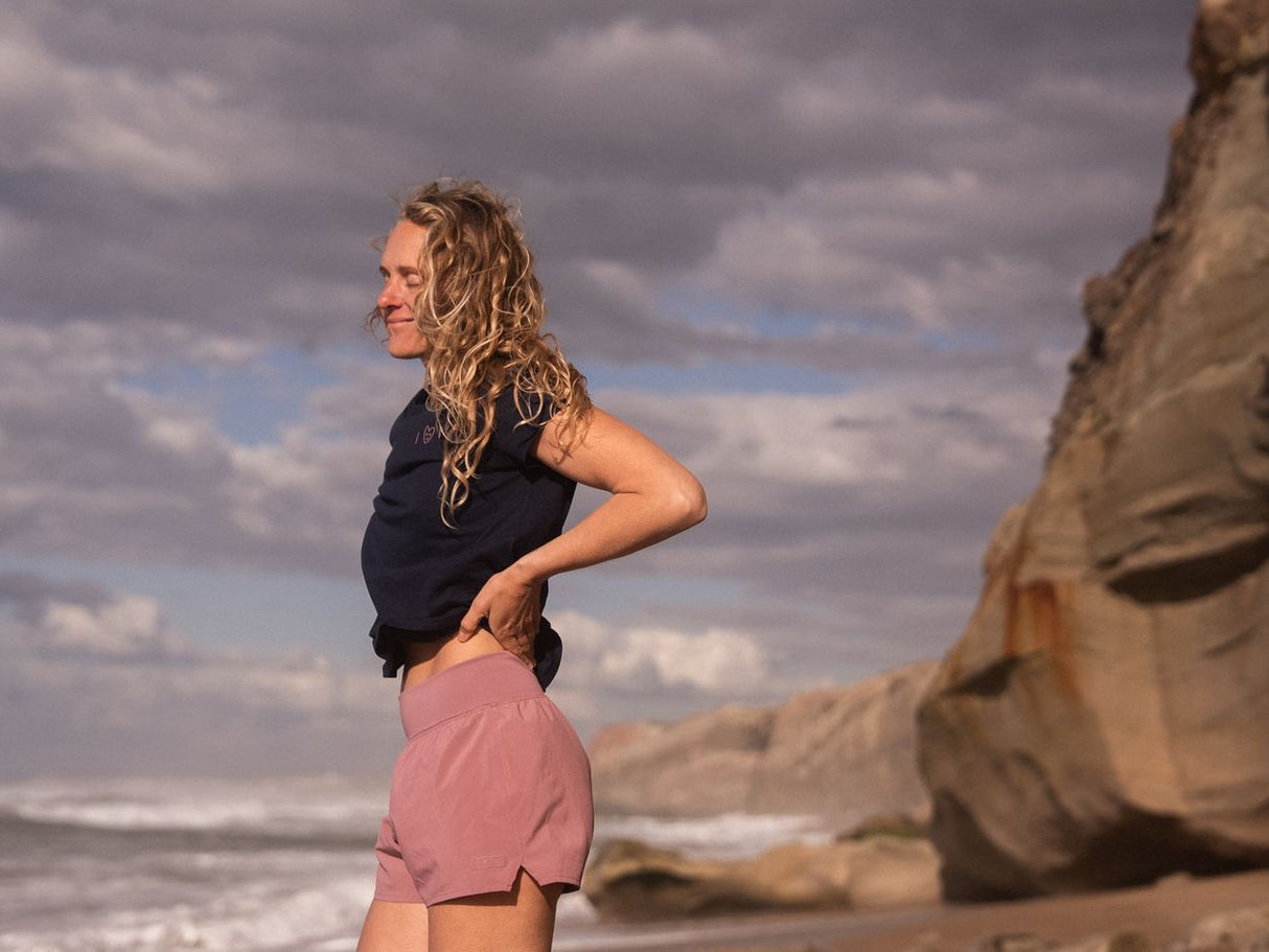 ION Ionic 2026 Neoprenanzug für Damen, schwarzes Oberteil und rosafarbene Shorts, Seitenansicht am Strand