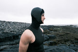 ION Hooded Neo Vest 3/2 schwarz mit Kapuze, seitliches Profil an Steinküste getragen