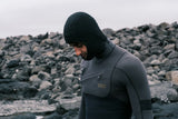 ION Neo Top Hooded Vest 2/1 dunkelblau mit Kapuze, Neopren-Oberteil, seitliche Ansicht an felsiger Küste