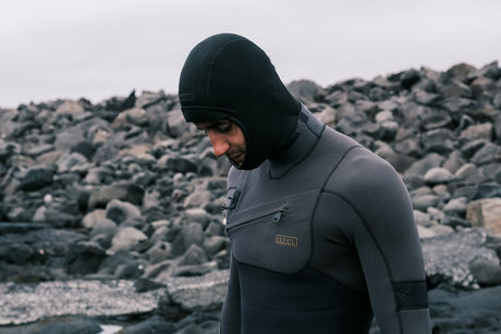 ION Neo Top Hooded Vest 2/1 dunkelblau mit Kapuze, Neopren-Oberteil, seitliche Ansicht an felsiger Küste