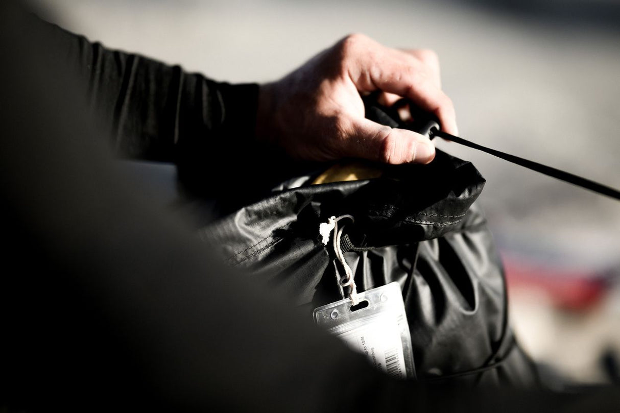 ION Kite Crushbag 2026 schwarz, Transporttasche mit Zugband, in Hand gehalten am Strand