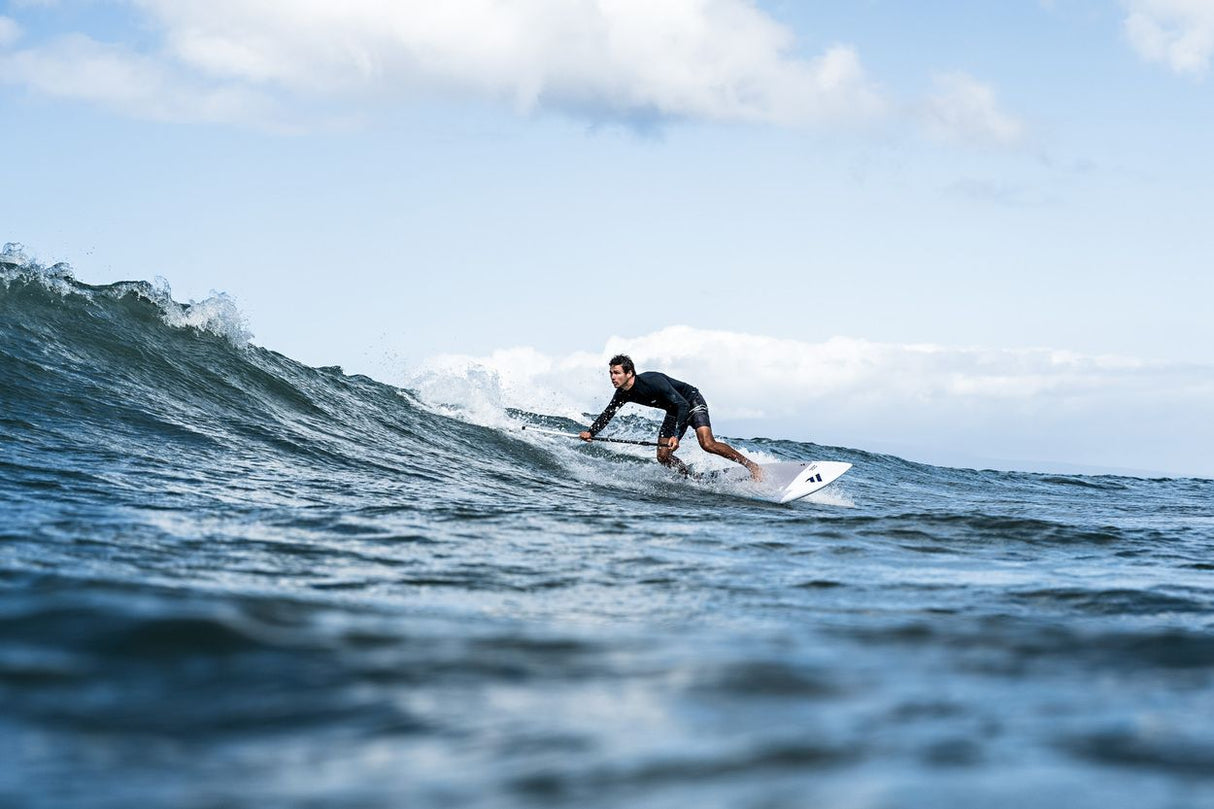 ION SUP Leash Core Coiled Ankle 2026, schwarze Spiralleine, am Knöchel getragen beim SUP-Surfen im Wasser