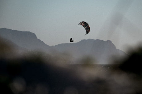 ION Core Long Sicherheitsleine 2026, schwarze Kitesurfing-Leine in Aktion über Wasser mit Bergkulisse