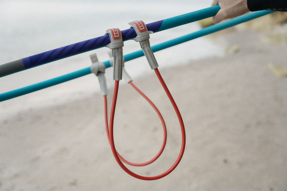 ION Harness Line 2026, rote Befestigungsleine mit metallischen Verschlüssen an blauem und türkisem Trapez, Detailansicht