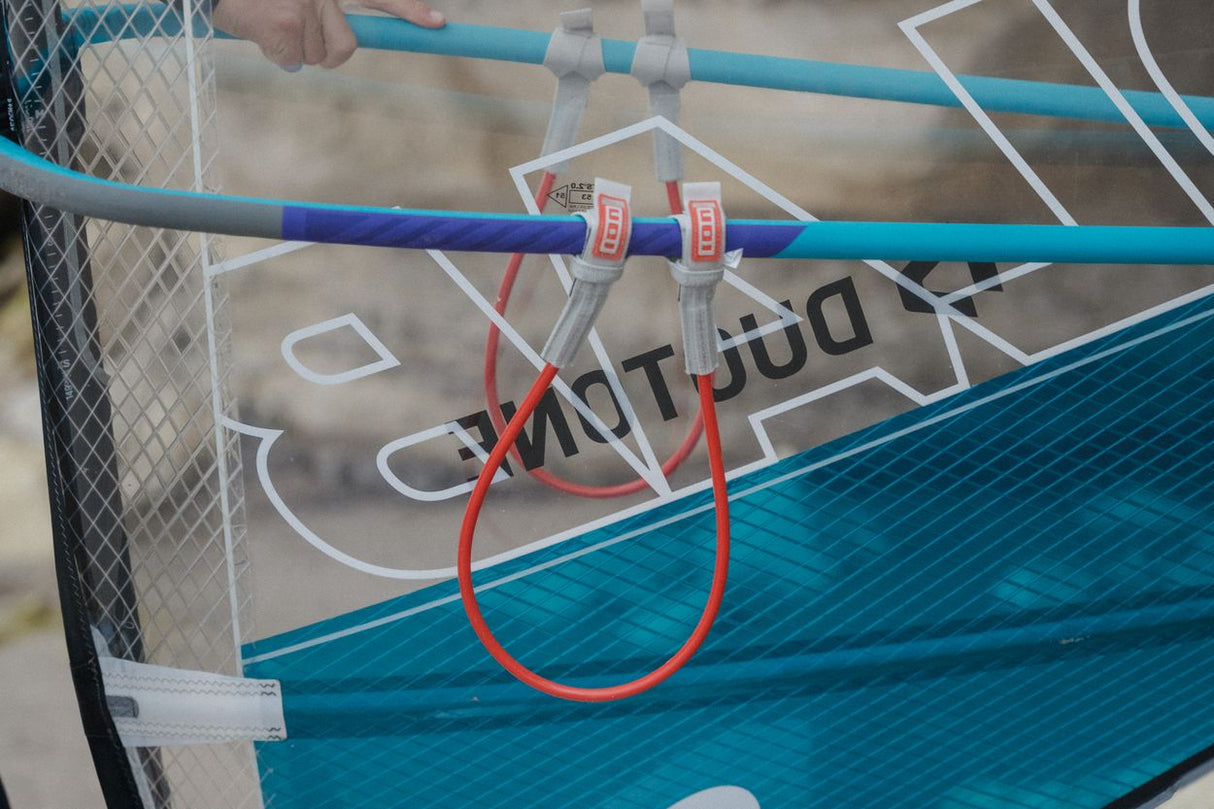ION Windsurf Harness Line Fix Pro 2026 mit roten Befestigungsriemen an Boom montiert, Detailansicht