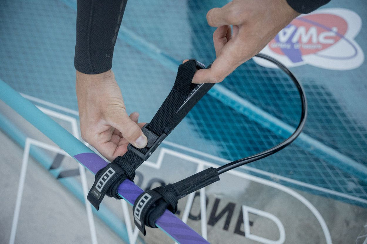 ION Windsurf Harness Line Vario 2026 schwarz mit Riemen, Detail-Nahaufnahme an Händen über Wasser