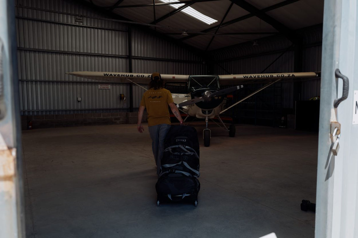 ION Gearbag Tec Golf 2026 schwarze Golftasche mit Rollen in Flugzeughalle, Frontansicht