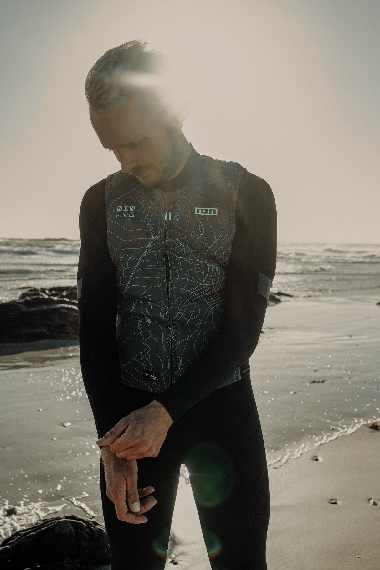 ION Vector Vest Core Herren 2024 schwarz mit Frontreisverschluss, Frontalansicht am Strand