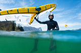 ION Hybrid Gloves 1+2.5 2026 schwarz, Kitesurfer hält gelbes Board im Wasser