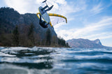 ION Hybrid Gloves 1+2.5 2026 schwarz, Kitesurfer in Aktion über Wasser mit Berg im Hintergrund