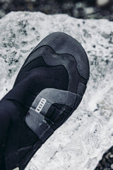 ION Ballistic Boots 3/2 schwarzer Neoprenanzug-Schuh mit geteilter Sohle, von oben auf Felsen fotografiert