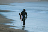 ION Ballistic Boots 3/2 Round Toe schwarz, Surfer am Strand mit Neoprenanzug und Surfboard, Ansicht von vorne