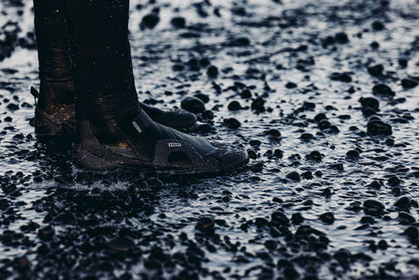 ION Ballistic Shoes 2.5 schwarz im Wasser, Seitenansicht mit Kieselsteinen, wasserfest