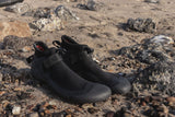 ION Ballistic Shoes 2.5 Round Toe 2026 schwarze Wassersportschuhe mit Neoprenmaterial auf steinigem Strand, Seitenansicht