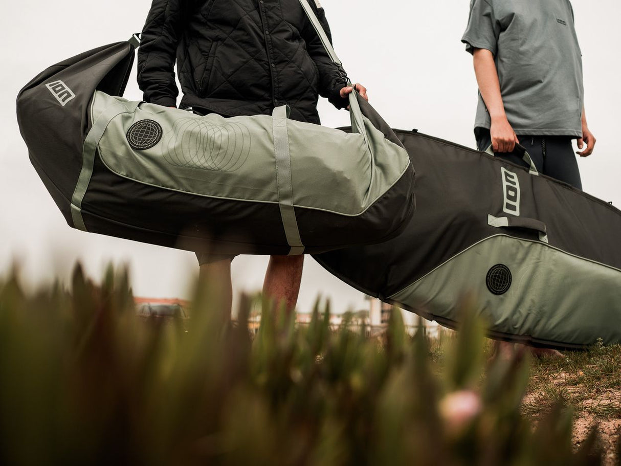 ION Wing Quiverbag Core 2026 in Schwarz und Grau, getragen von Person in Outdoor-Umgebung, Transporttasche für Wassersportausrüstung