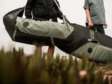 ION Wing Quiverbag Core 2026 in Schwarz und Grau, getragen von Person in Outdoor-Umgebung, Transporttasche für Wassersportausrüstung