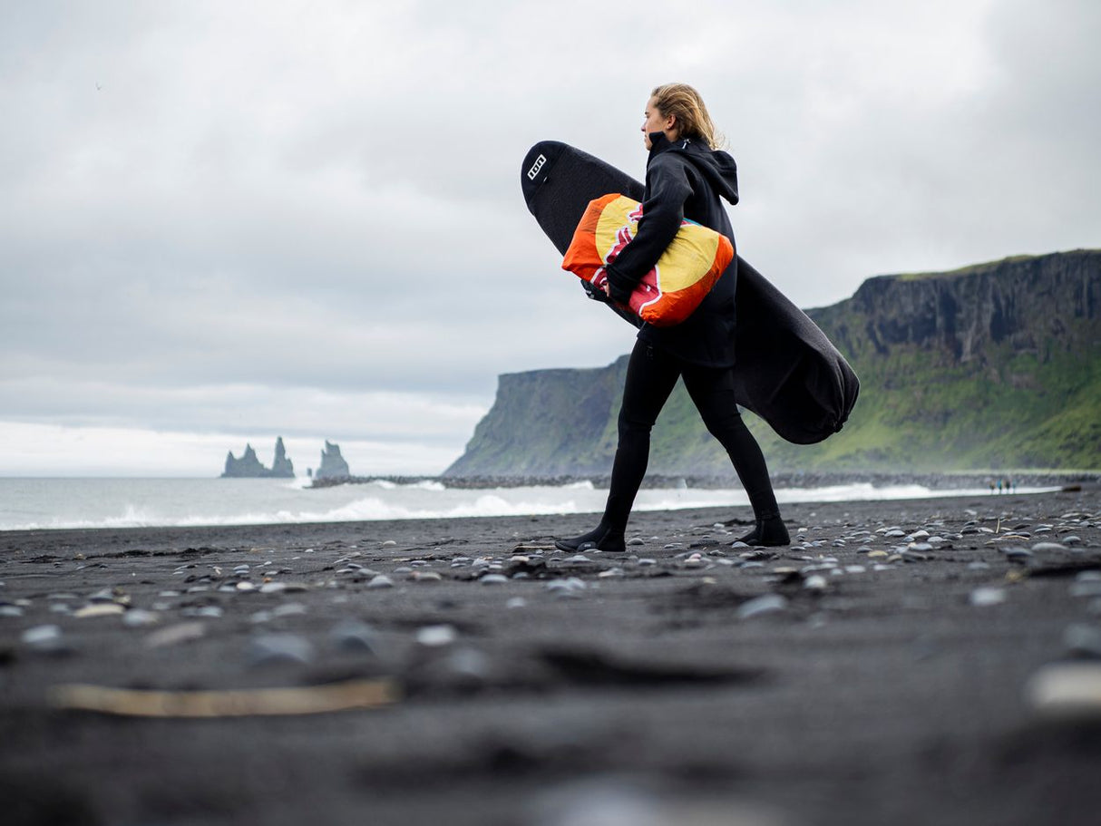 ION Surf Sock Stubby 2024 SS schwarze Neopren-Socke, Surfer trägt sie am Strand mit Surfboard