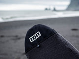 ION Surf Sock Stubby 2024 SS in Dunkelblau und Grau, Neopren-Socke am Strand, Nahaufnahme mit ION-Logo