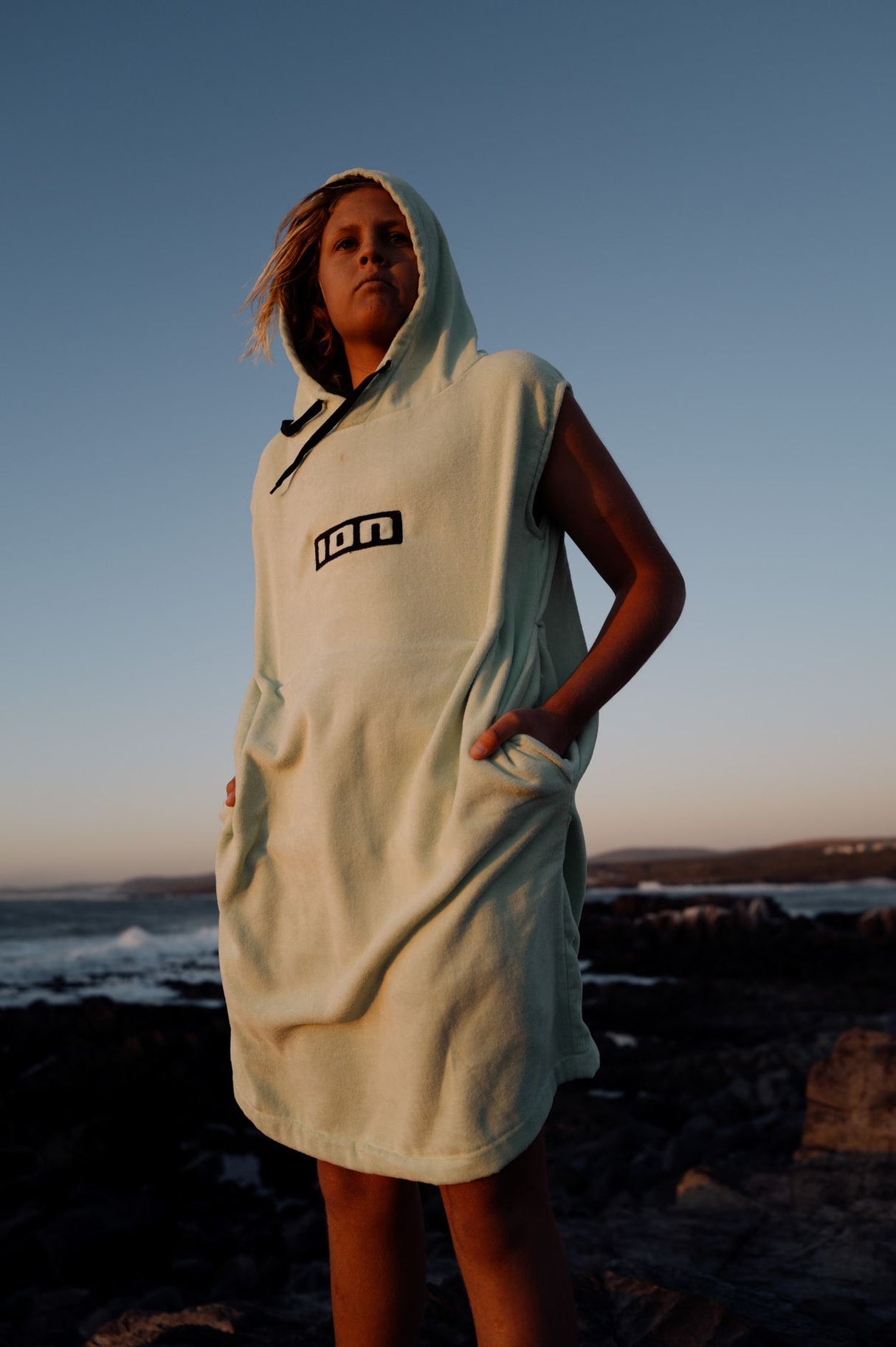 ION Grom 2025 Poncho aus Baumwolle in Creme mit Kapuze, Frontansicht am Strand
