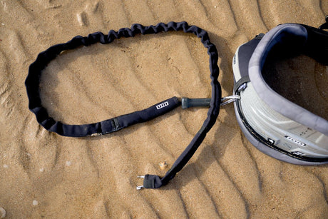 ION Handle Pass Leash Comp 2026 Trapezleash schwarz mit Elastik und Metallkarabiner am Sand