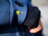 ION Neo Shelter Jacket Amp Herren 2024 in Blau mit gelbem Logo-Detail, Nahaufnahme des Ärmels