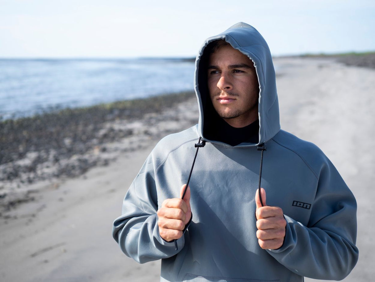 ION Neo Hoody Lite Men 2025 in Blau, Neopren-Hoodie mit Kapuze, am Strand getragen, Frontalansicht