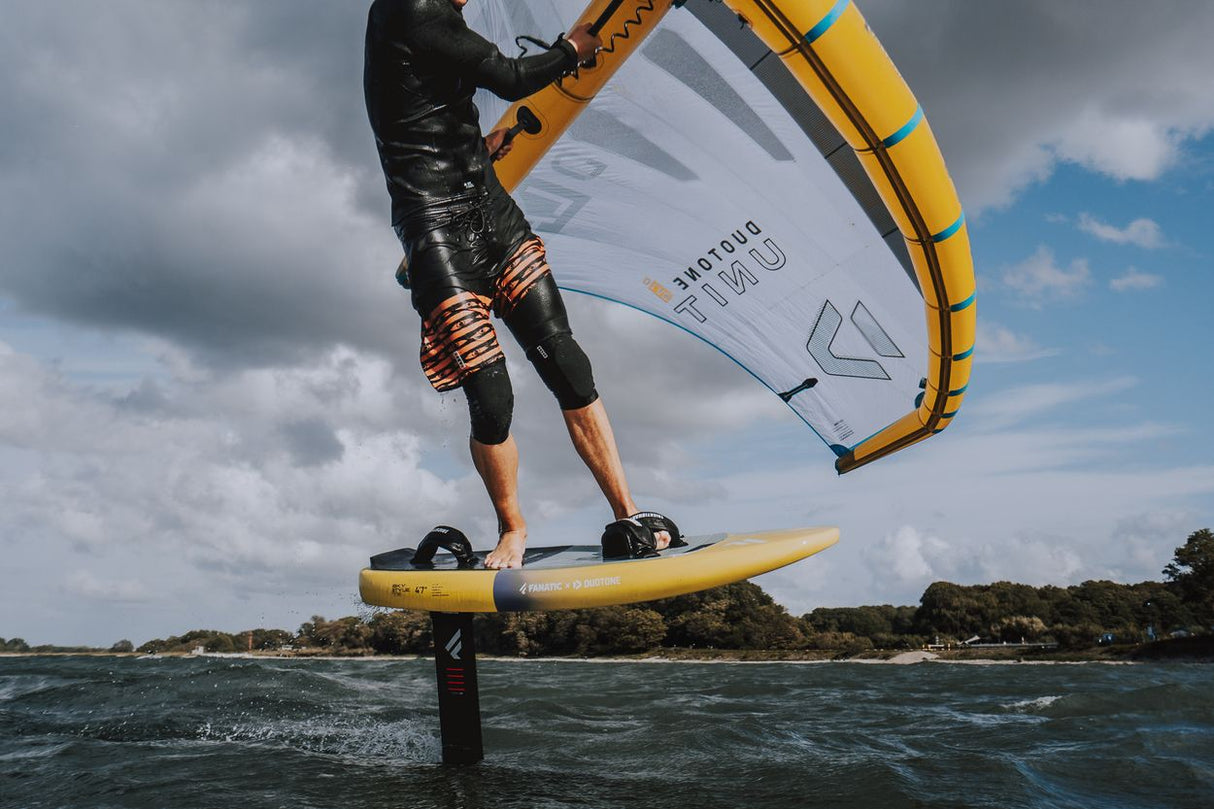 ION Neo Zip Top 2/1 LS schwarz mit orange Details, Kitesurfer in Aktion auf dem Wasser