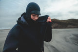 ION Neo Cosy Coat 2026 in Dunkelblau, Neopren-Jacke mit Kapuze, Frontalansicht am Strand getragen