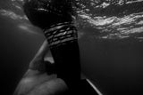 ION Wing Knee Sleeve 2026 schwarz mit Riemen, Unterwasser-Seitenansicht am Bein getragen
