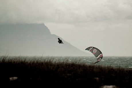 ION Amp Long 2026 Kite in Aktion über Wasser, Kitesurfer in Bewegung, grauer Himmel, Berglandschaft
