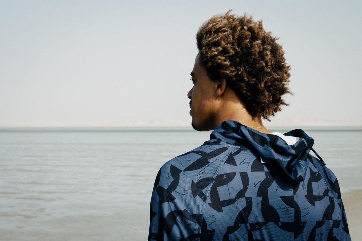 ION Wetshirt Hood Langarm Herren 2026 in Blau mit geometrischem Muster, Rückansicht am Meer