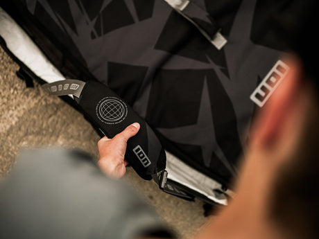 ION Wing Boardbag Tec 2026 Transporttasche in Schwarz mit geometrischem Muster, in Hand gehalten