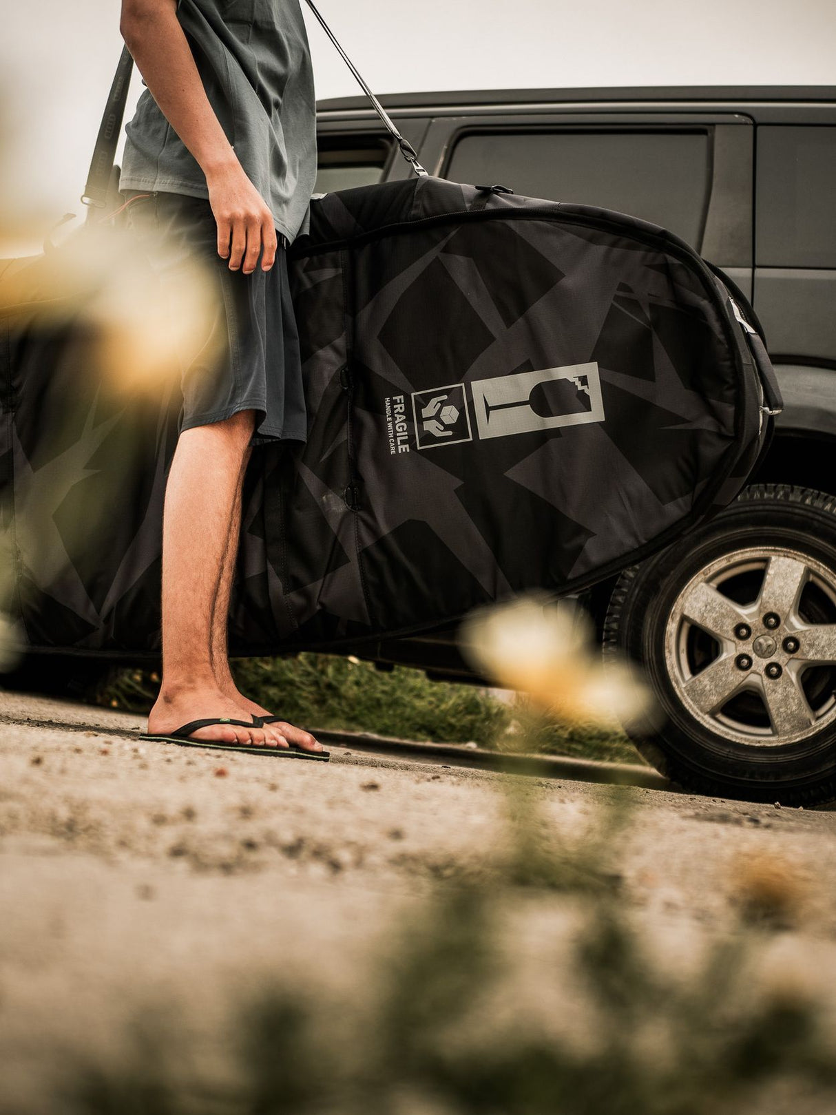 ION Wing Boardbag Tec 2026 schwarze Transporttasche am Auto, Frontalansicht mit Tragegriffen