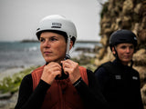 ION Slash Core Helm weiß, Sportschutzhelm mit Kinnriemen, Frontalansicht auf Person am Strand
