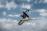 ION Slash Amp 2026 Kite in Luftsprung vor bewölktem Himmel, schwarzes Segel mit gelbem Gestänge