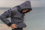 ION Neo Hoody Reversible 2026, Neopren-Jacke mit Kapuze, Grau mit Muster, wasserabweisend, Frontalansicht am Strand getragen