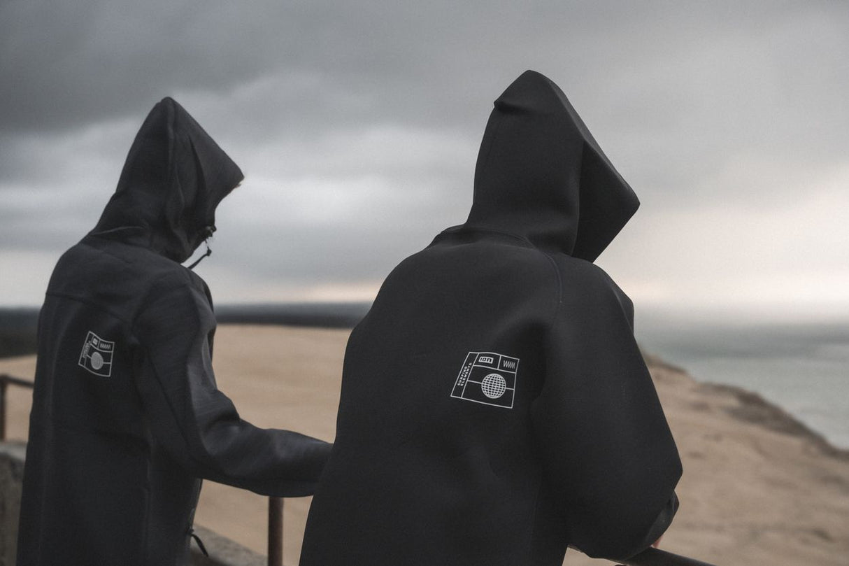 ION Neo Hoody Reversible 2026 in Schwarz, Neopren-Kapuzenpullover, Rückansicht von zwei Personen am Strand