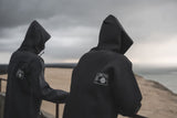ION Neo Hoody Reversible 2026 in Schwarz, Neopren-Kapuzenpullover, Rückansicht von zwei Personen am Strand