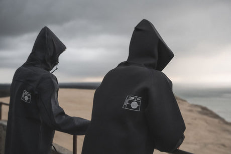 ION Neo Hoody Reversible 2026 in Schwarz, Neopren-Kapuzenpullover, Rückansicht von zwei Personen am Strand